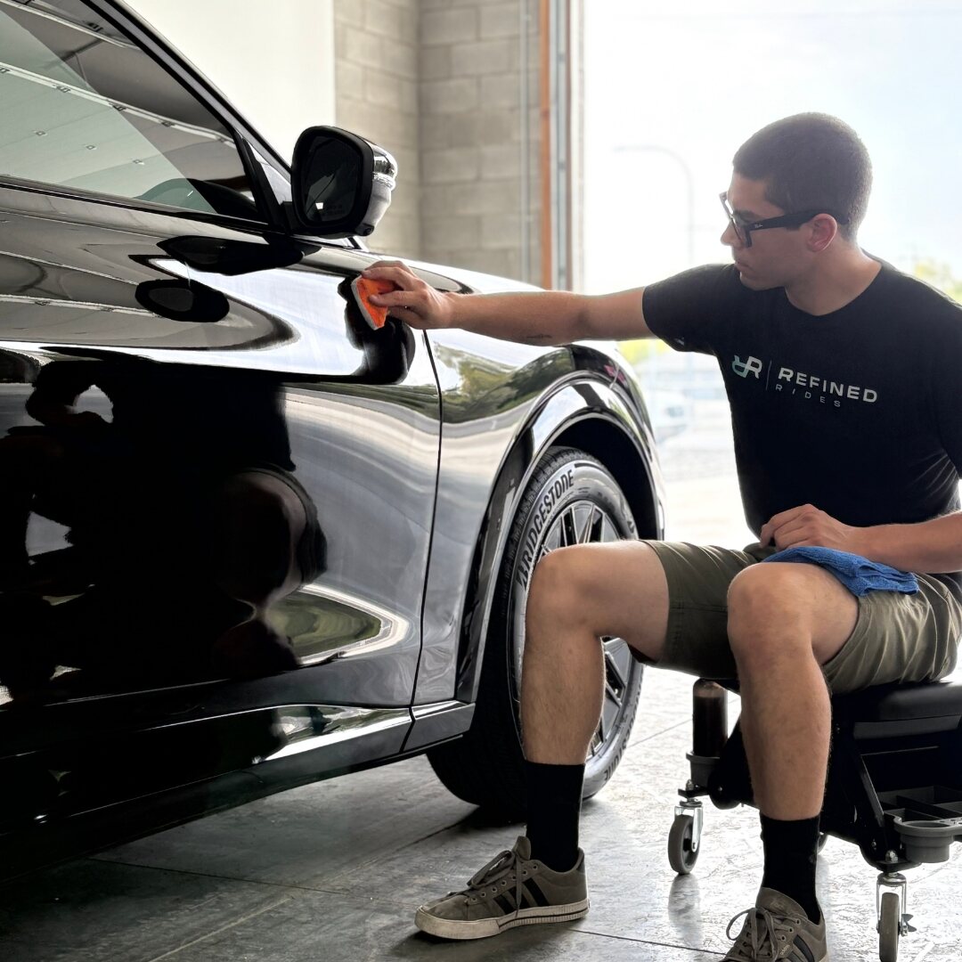 Refined Rides technician hand applying ceramic coating to a black vehicle at the Yakima shop