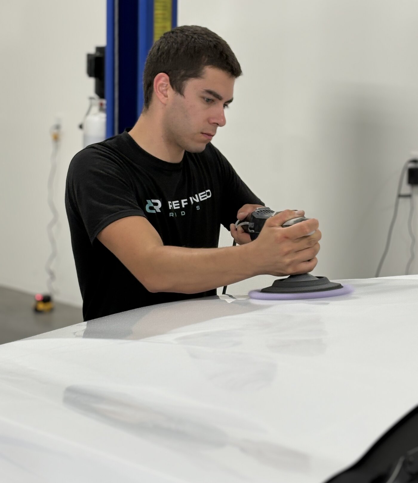 Refined Rides technician machine polishing a white vehicle panel during paint correction in Yakima, WA